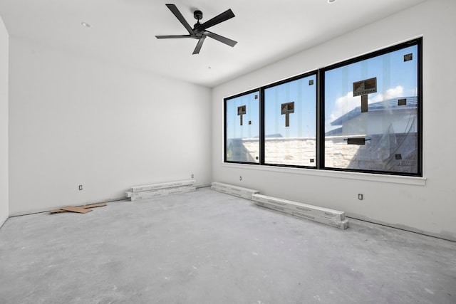 unfurnished room with ceiling fan and concrete flooring