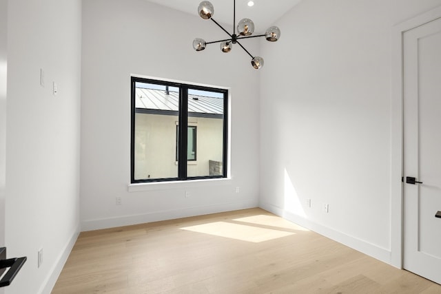 empty room with a chandelier and light hardwood / wood-style floors