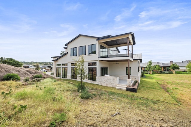 rear view of house featuring a balcony, a yard, a patio, and ceiling fan