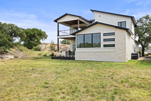 back of house featuring a lawn and a balcony