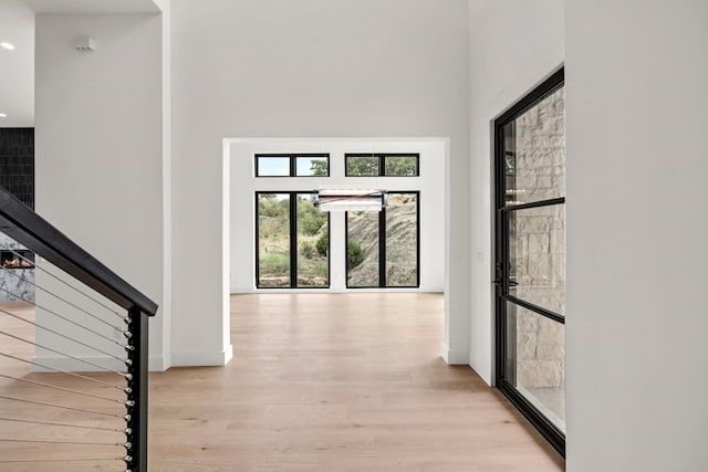 hall with a high ceiling and light wood-type flooring