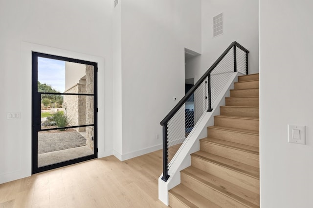 entryway featuring a towering ceiling and light hardwood / wood-style flooring