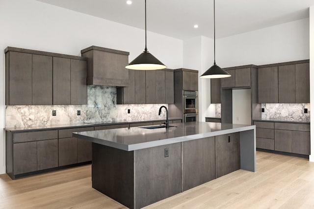 kitchen with decorative backsplash, light hardwood / wood-style flooring, dark brown cabinets, sink, and pendant lighting