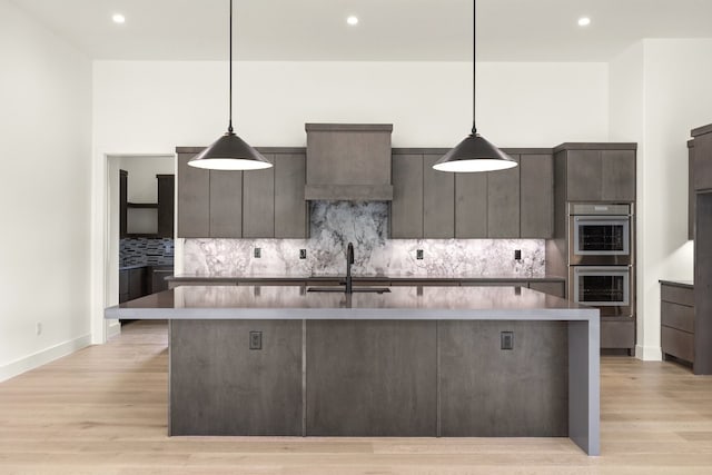 kitchen with sink, light hardwood / wood-style flooring, dark brown cabinets, and pendant lighting