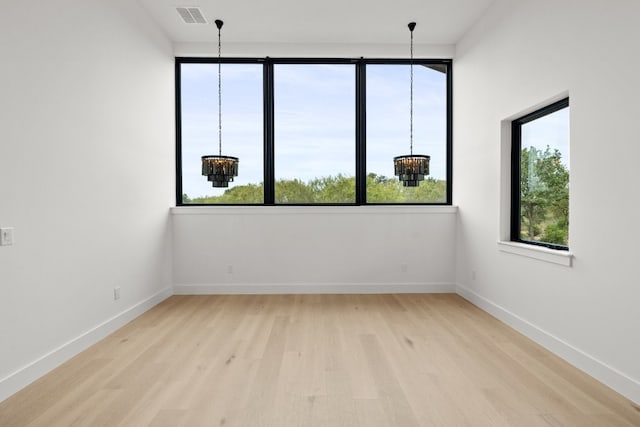 empty room with a notable chandelier and light wood-type flooring