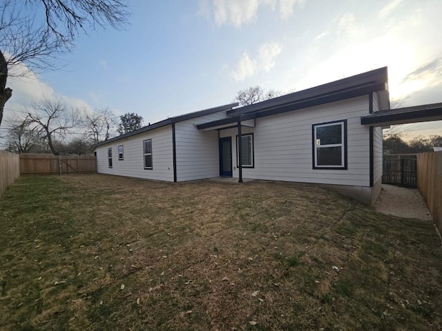 rear view of house with a yard and a fenced backyard