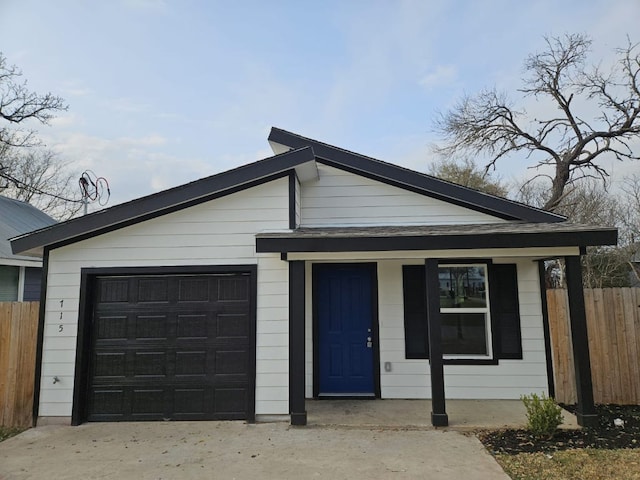 view of front facade featuring a porch, concrete driveway, a garage, and fence