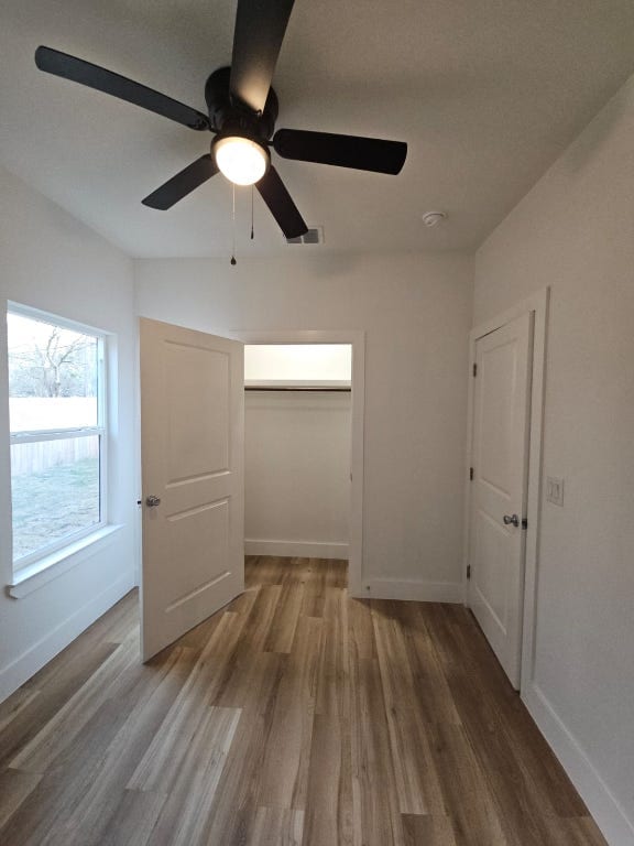 unfurnished bedroom with ceiling fan, wood finished floors, visible vents, and baseboards