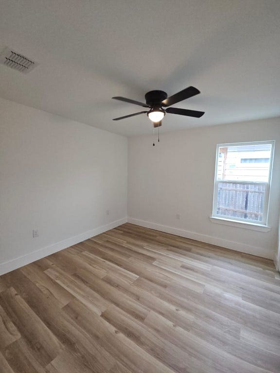 empty room featuring light wood finished floors, visible vents, ceiling fan, and baseboards