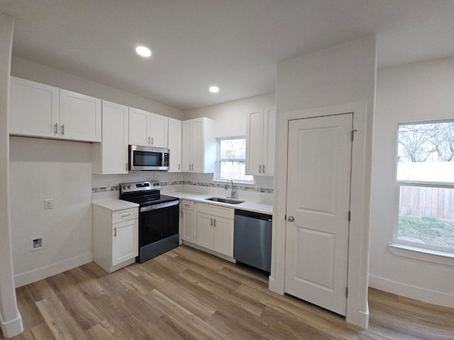 kitchen with a sink, stainless steel appliances, tasteful backsplash, and white cabinetry