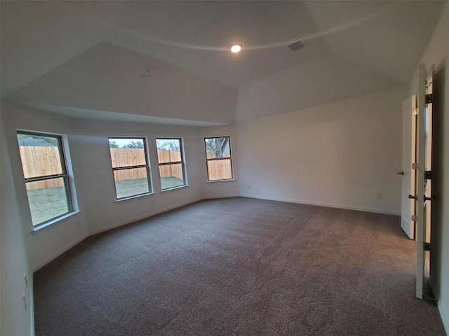 spare room with dark colored carpet, vaulted ceiling, and a wealth of natural light