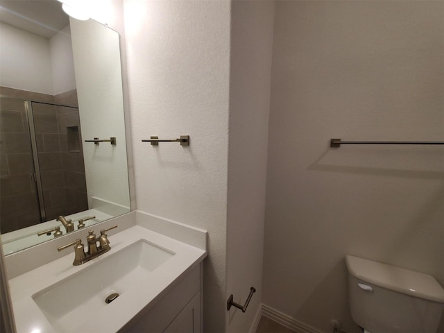 bathroom with vanity, tiled shower, and toilet