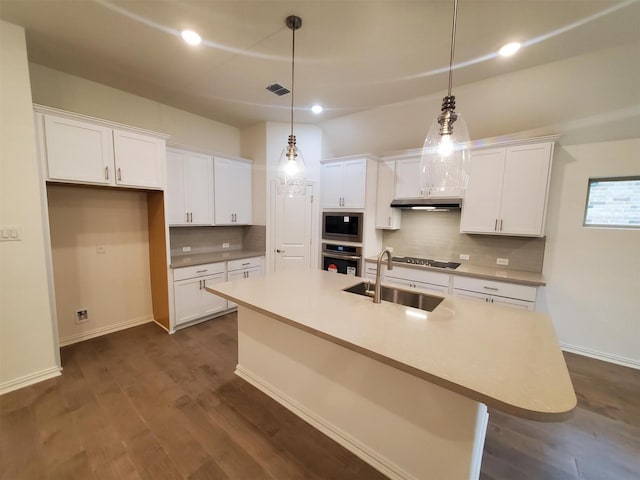 kitchen featuring pendant lighting, sink, white cabinetry, a kitchen island with sink, and oven