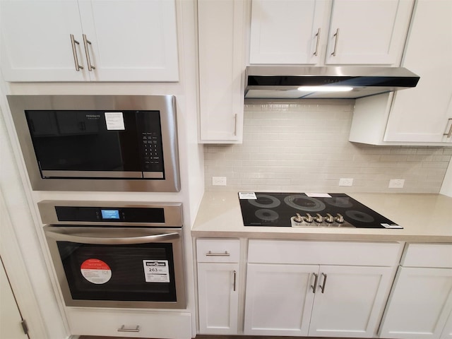 kitchen featuring white cabinetry, stainless steel oven, backsplash, and black electric cooktop