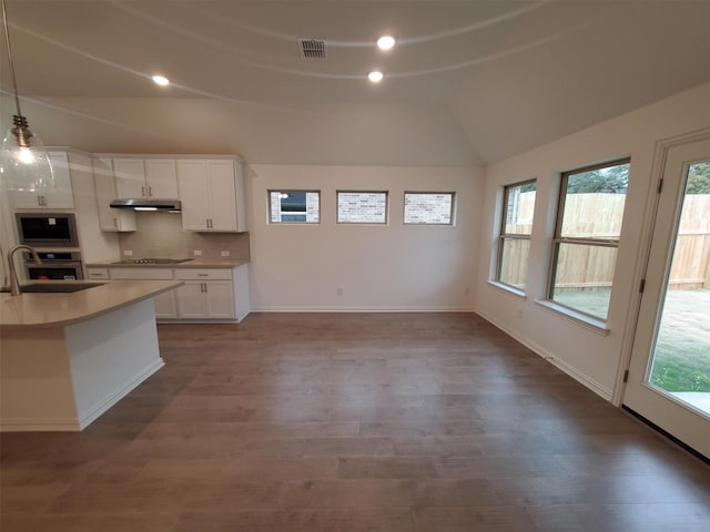 kitchen with decorative light fixtures, built in microwave, white cabinetry, lofted ceiling, and sink