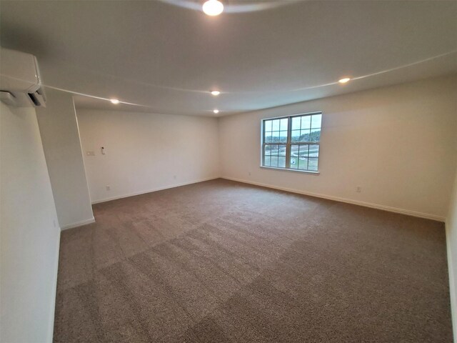 empty room featuring a wall unit AC and dark colored carpet