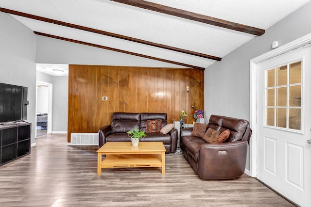 living room featuring lofted ceiling with beams, wood walls, and light hardwood / wood-style floors