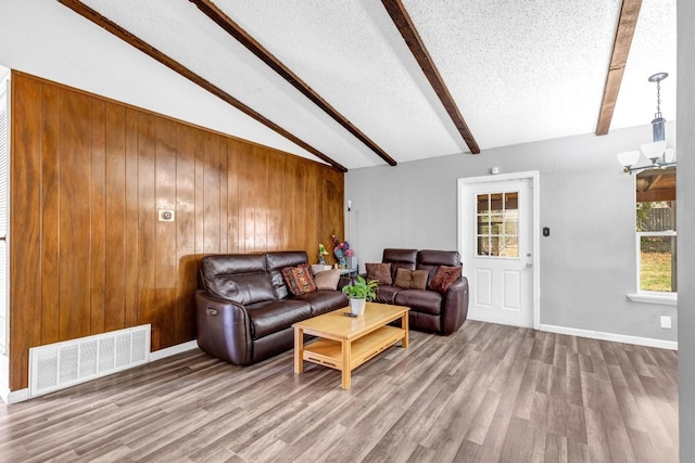 living room featuring wooden walls, lofted ceiling with beams, hardwood / wood-style floors, and plenty of natural light