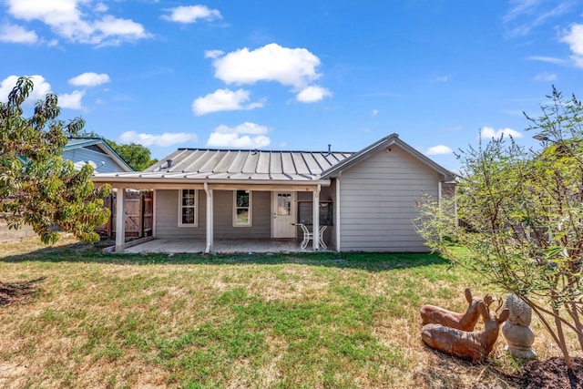 back of house featuring a lawn and a patio