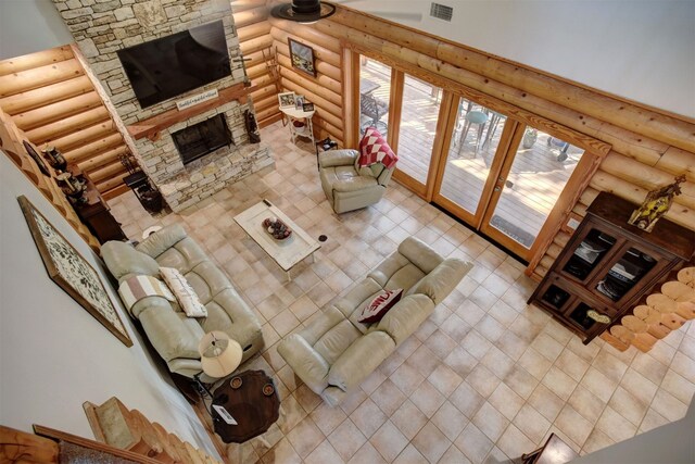 living room with french doors, a stone fireplace, and rustic walls