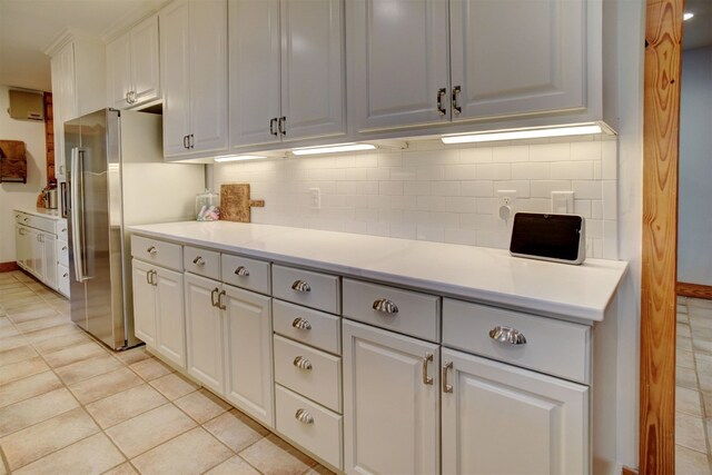 kitchen featuring tasteful backsplash, light tile patterned floors, high end refrigerator, and white cabinetry