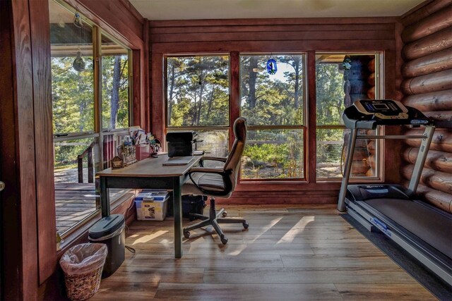 home office featuring hardwood / wood-style flooring, log walls, and a wealth of natural light