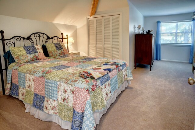 carpeted bedroom featuring lofted ceiling with beams and a closet