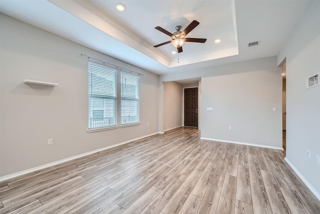 empty room with ceiling fan, light hardwood / wood-style floors, and a raised ceiling