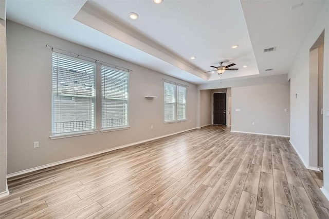 empty room featuring a tray ceiling, light hardwood / wood-style flooring, and ceiling fan