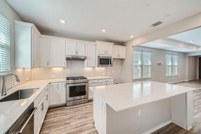 kitchen with white cabinets, sink, stainless steel appliances, and light hardwood / wood-style flooring