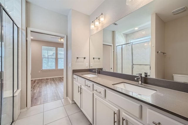 bathroom with vanity, ceiling fan, toilet, an enclosed shower, and wood-type flooring