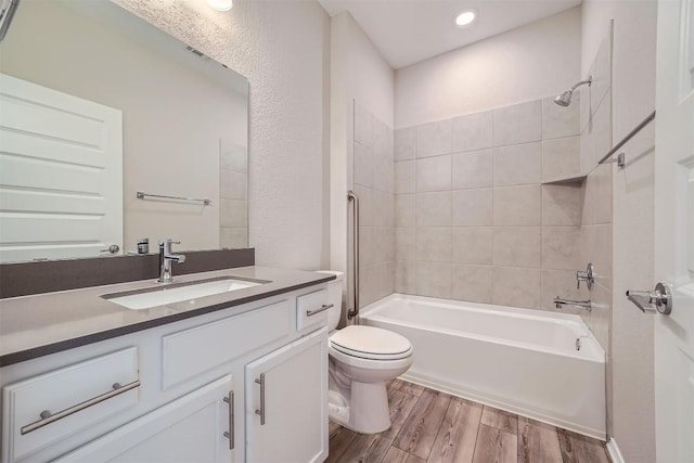 full bathroom featuring hardwood / wood-style floors, vanity, toilet, and tiled shower / bath