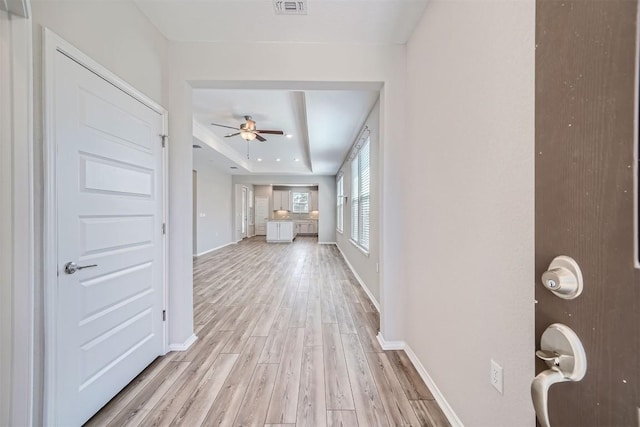 hallway featuring a raised ceiling and light wood-type flooring