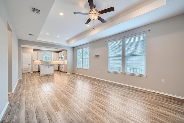 unfurnished living room with ceiling fan, light hardwood / wood-style floors, crown molding, and a tray ceiling