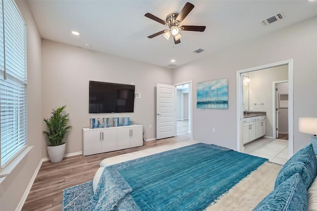 bedroom with ceiling fan, light hardwood / wood-style floors, ensuite bath, and multiple windows