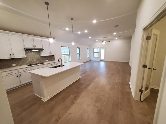 kitchen featuring sink, black electric cooktop, a kitchen island with sink, decorative backsplash, and white cabinets