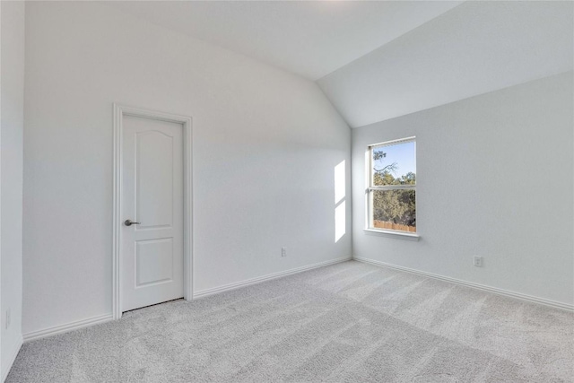 spare room featuring vaulted ceiling and light carpet