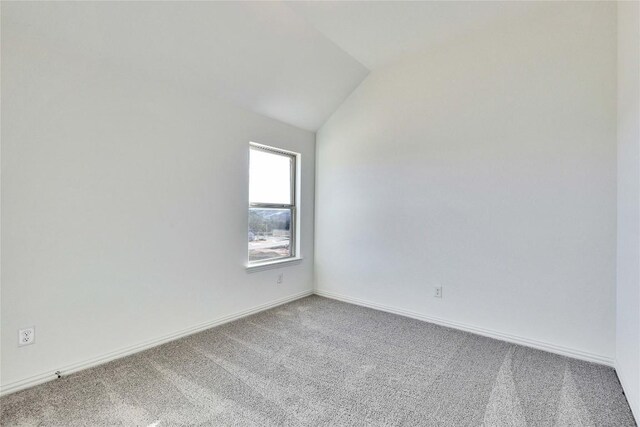 carpeted empty room featuring vaulted ceiling