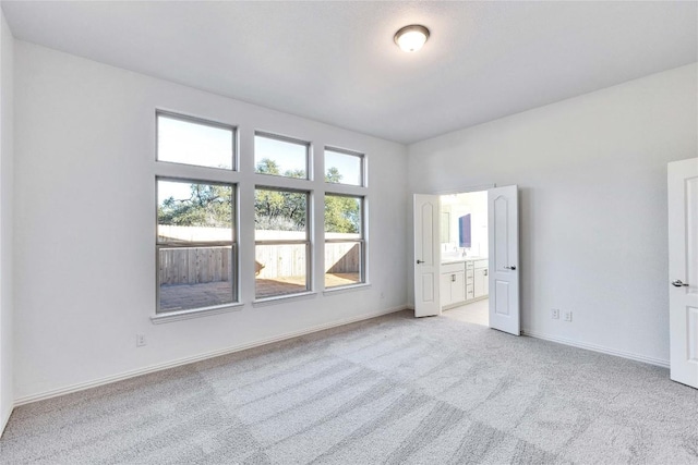 unfurnished bedroom with connected bathroom and light colored carpet