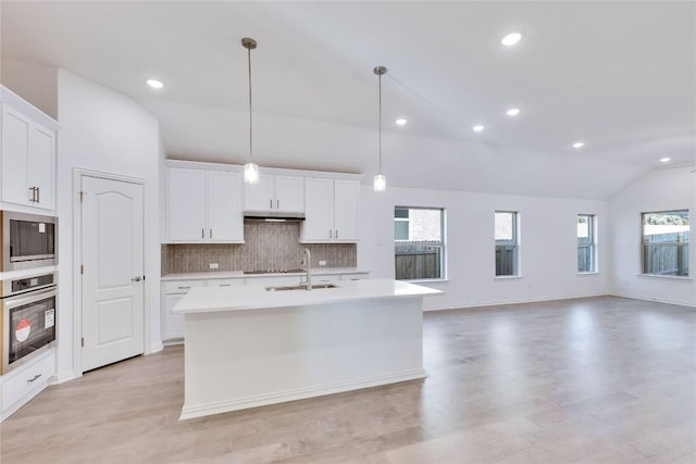 kitchen featuring built in microwave, a kitchen island with sink, white cabinets, and oven