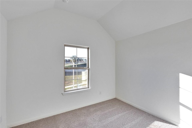 spare room featuring vaulted ceiling and carpet floors