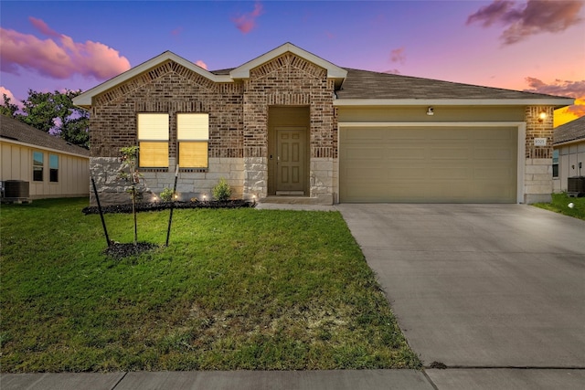 view of front of house featuring a garage, central AC unit, and a yard