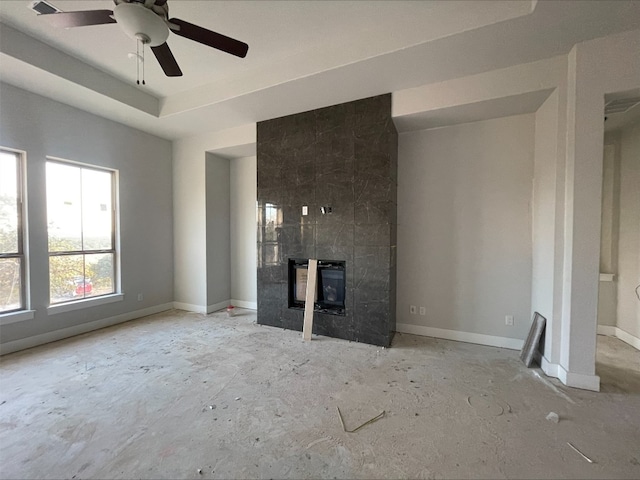 unfurnished living room featuring a tiled fireplace and ceiling fan