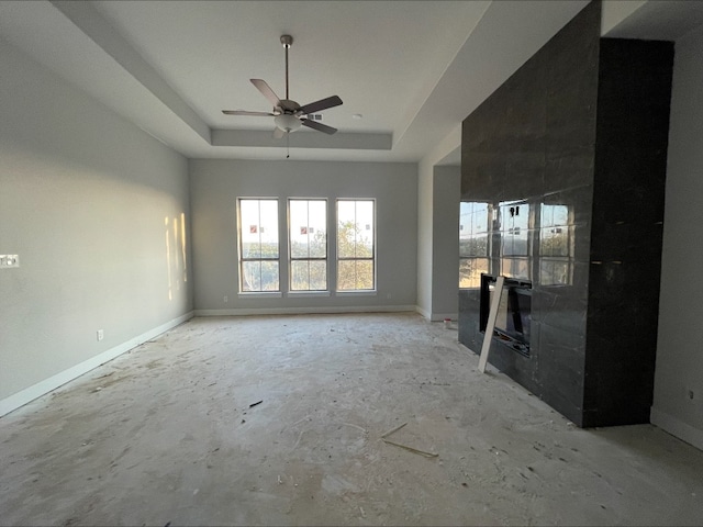 unfurnished living room with a raised ceiling and ceiling fan