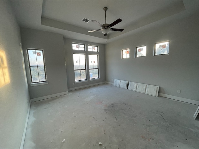 empty room with a raised ceiling and ceiling fan