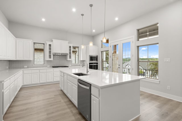 kitchen featuring tasteful backsplash, sink, white cabinets, a kitchen island with sink, and black appliances