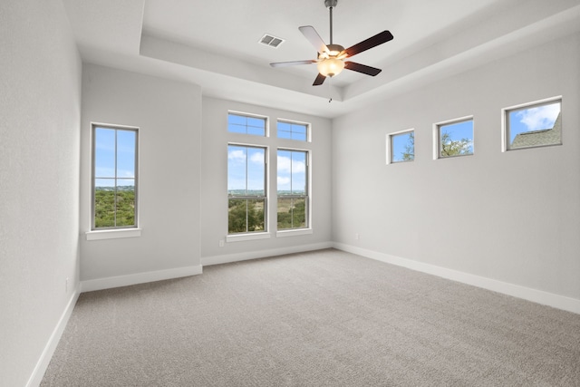 carpeted spare room featuring a raised ceiling and ceiling fan