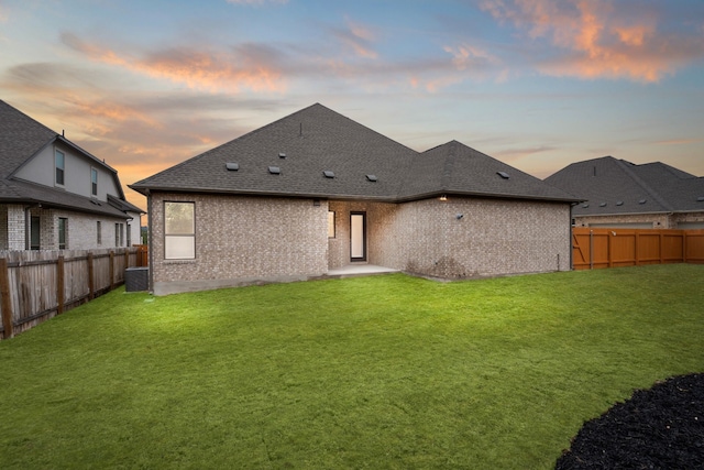 back house at dusk featuring a yard