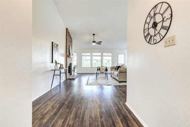 living room with ceiling fan, a fireplace, and dark wood-type flooring