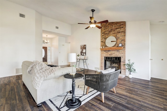 living room featuring lofted ceiling, ceiling fan with notable chandelier, a fireplace, and dark hardwood / wood-style floors